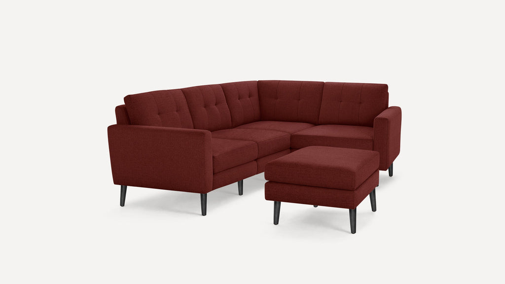 Modern mid-century style sectional sofa with matching ottoman, upholstered in deep burgundy fabric and supported by black wooden legs.