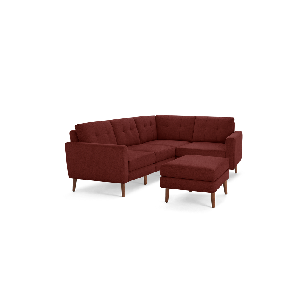 Mid-century style sectional sofa in deep red fabric with tufted back cushions and matching ottoman, supported by wooden legs.