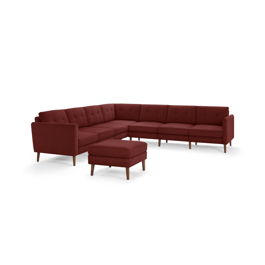 Modern L-shaped sectional sofa in deep red fabric with tufted back cushions and wooden legs, accompanied by a matching ottoman.