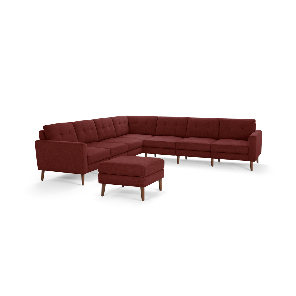 Large modern L-shaped sectional sofa with deep red fabric upholstery and wooden legs, accompanied by a matching ottoman.