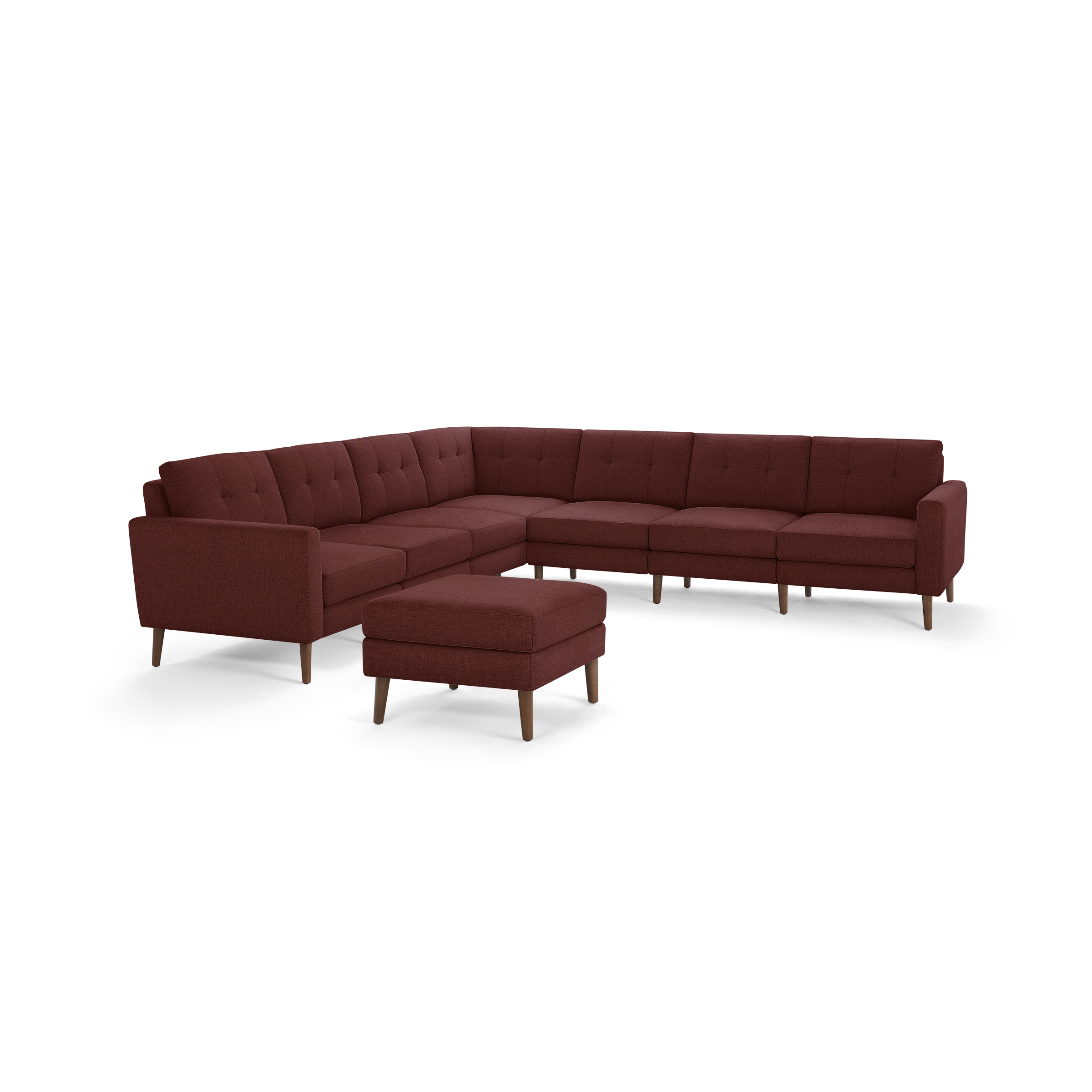 Large modern L-shaped sectional sofa with deep red fabric upholstery and wooden legs, accompanied by a matching ottoman.