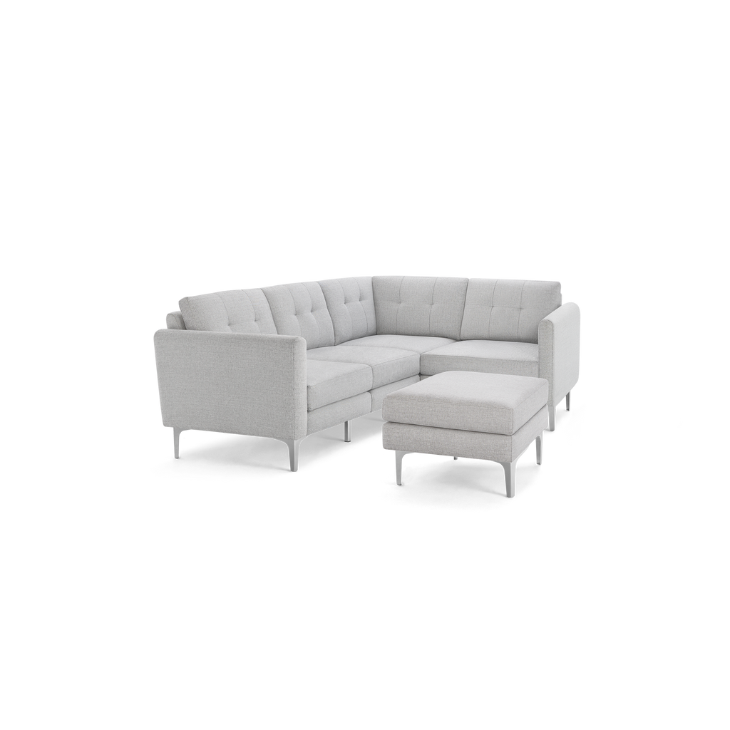 Light gray modern L-shaped sectional sofa with tufted cushions, high armrests, and matching ottoman on slim legs.