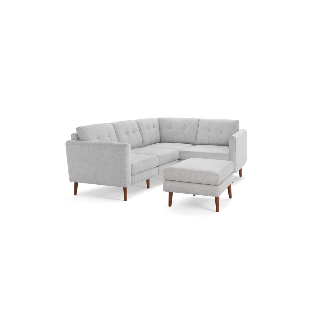 Light gray tufted fabric sectional sofa with wooden legs and matching ottoman, modern mid-century design.