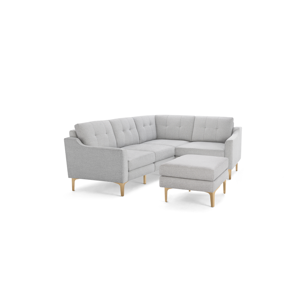Light gray fabric sectional sofa with tufted back cushions, wooden legs, and matching ottoman.