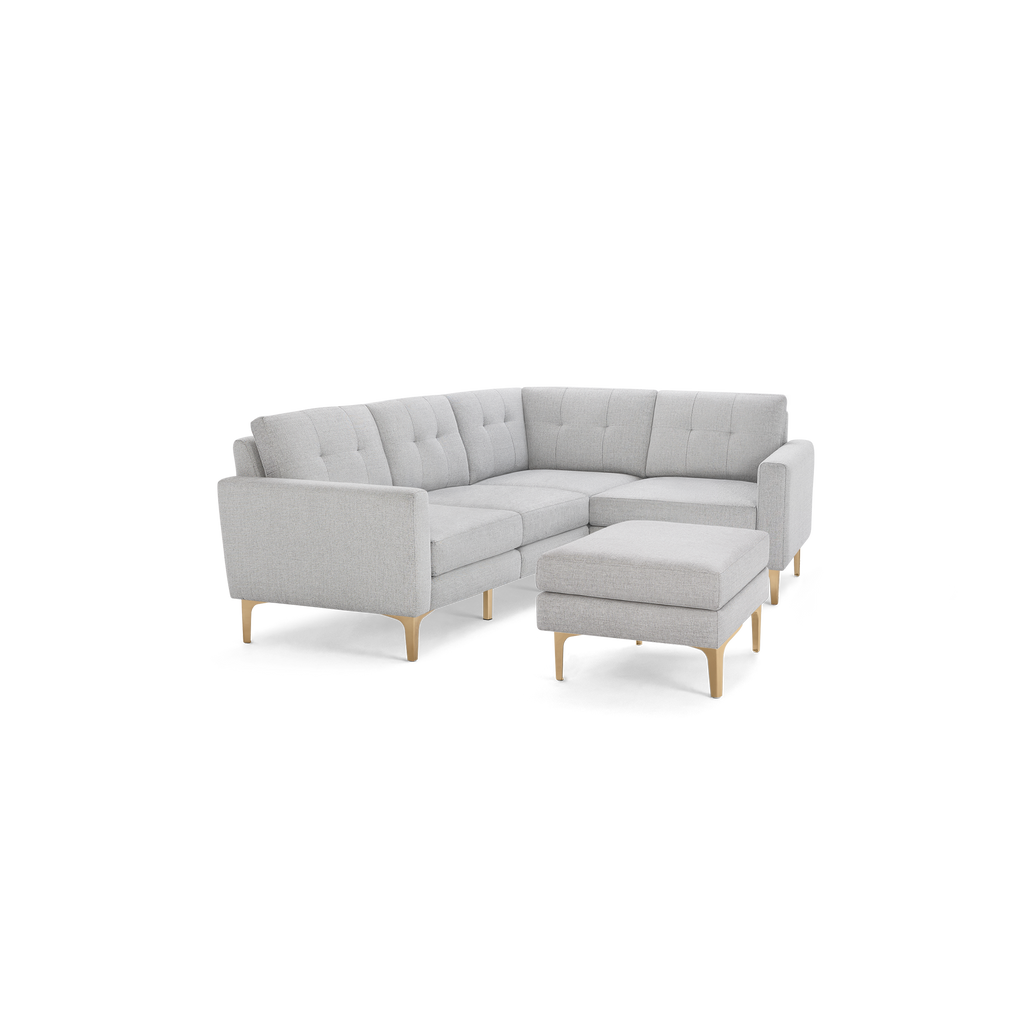 Light gray fabric sectional sofa with tufted cushions and wooden legs, including a matching ottoman.