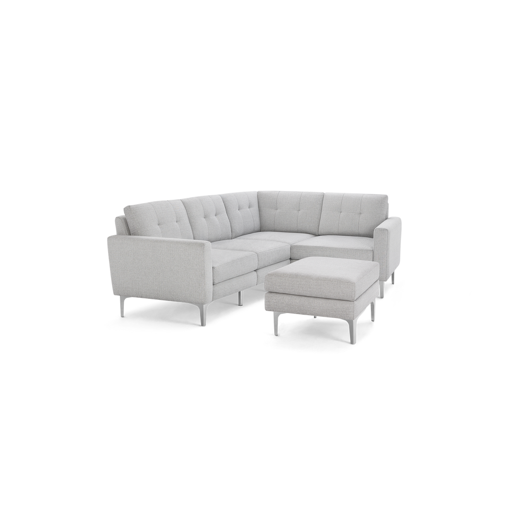 Light gray L-shaped sectional sofa with tufted back cushions and matching ottoman, supported by slim metal legs.
