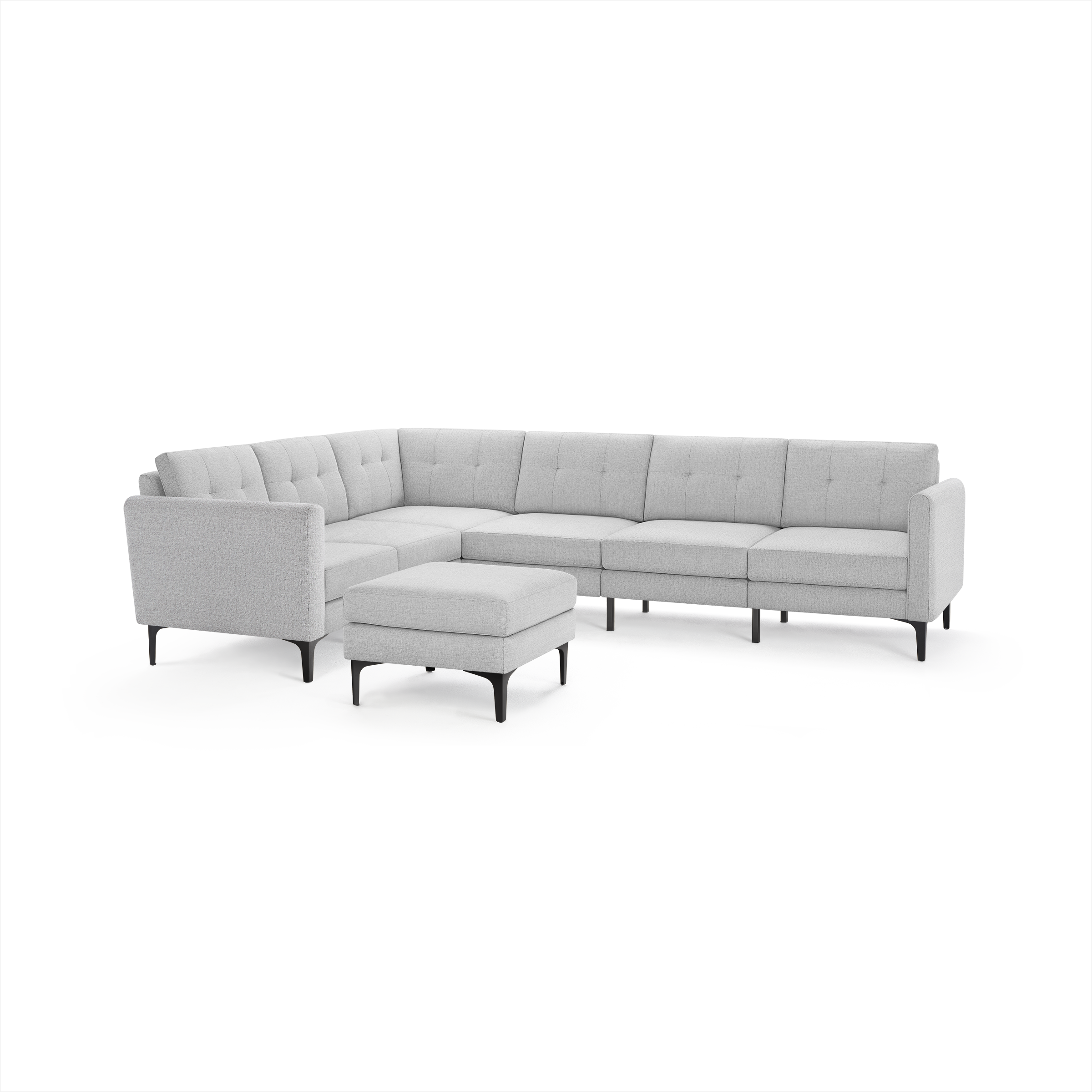 Light gray L-shaped sectional sofa with tufted cushions and matching ottoman on black tapered legs.