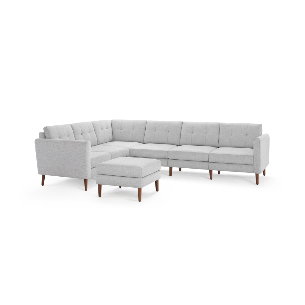 Light gray modern sectional sofa with tufted cushions and wooden legs, including a matching ottoman.