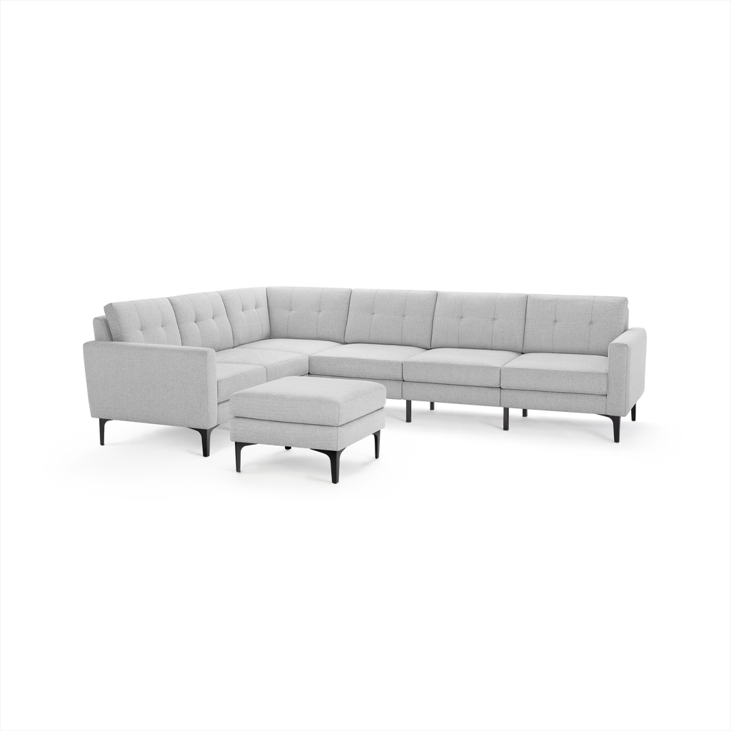 Light gray L-shaped sectional sofa with tufted cushions and black tapered legs, accompanied by a matching ottoman.