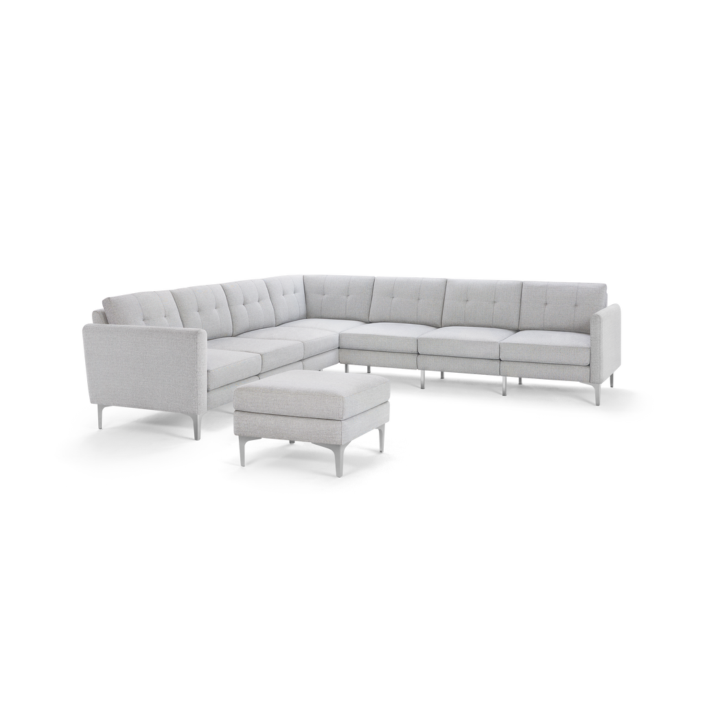 Light gray L-shaped modern sectional sofa with tufted cushions and matching ottoman, supported by slender metal legs.