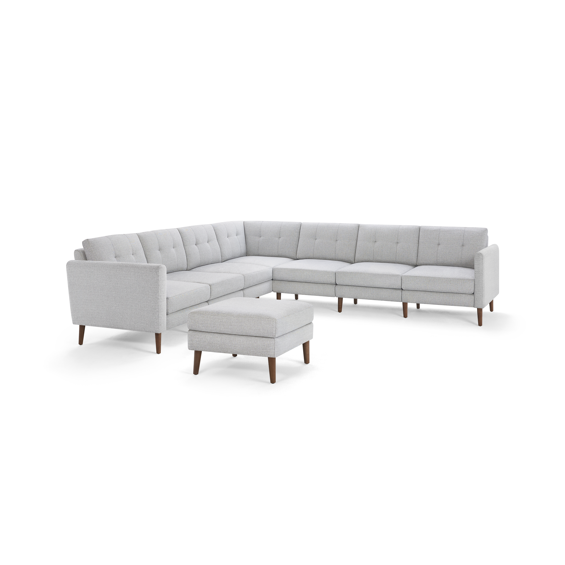 Light gray fabric sectional sofa with tufted cushions and wooden legs, accompanied by a matching ottoman.