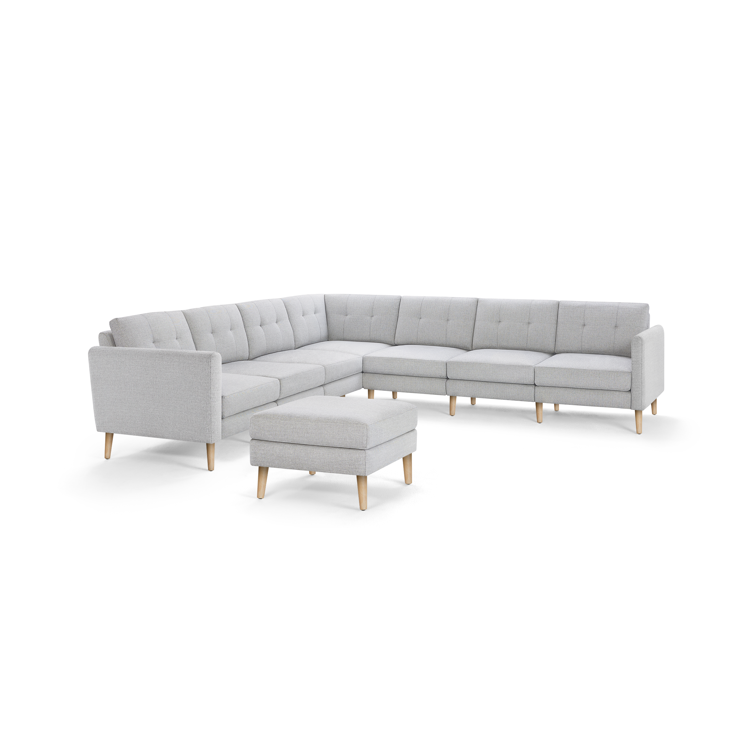 Light gray fabric sectional sofa with tufted cushions and wooden legs, accompanied by a matching ottoman.