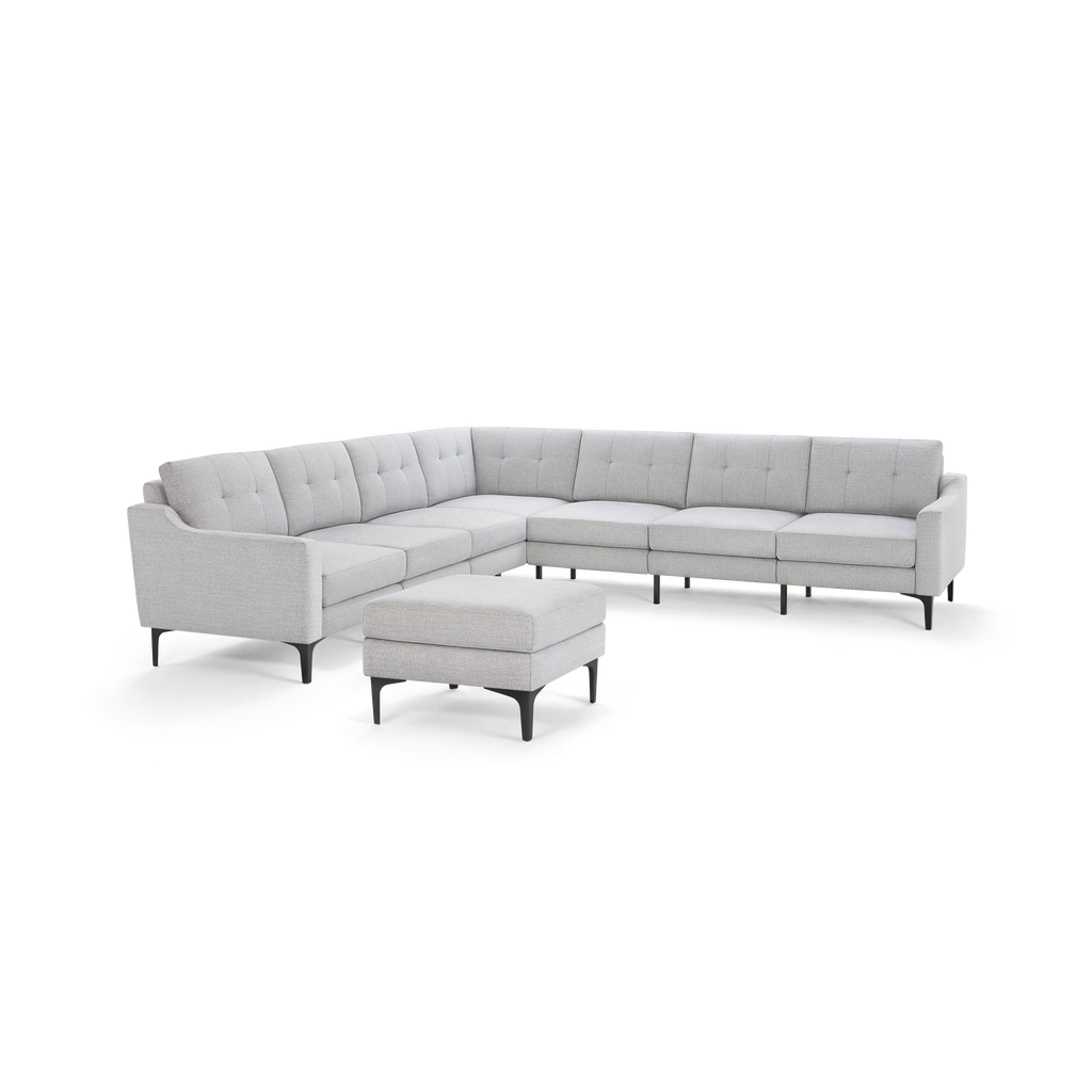 Light gray modern L-shaped sectional sofa with tufted back cushions and matching ottoman, supported by slim black legs.