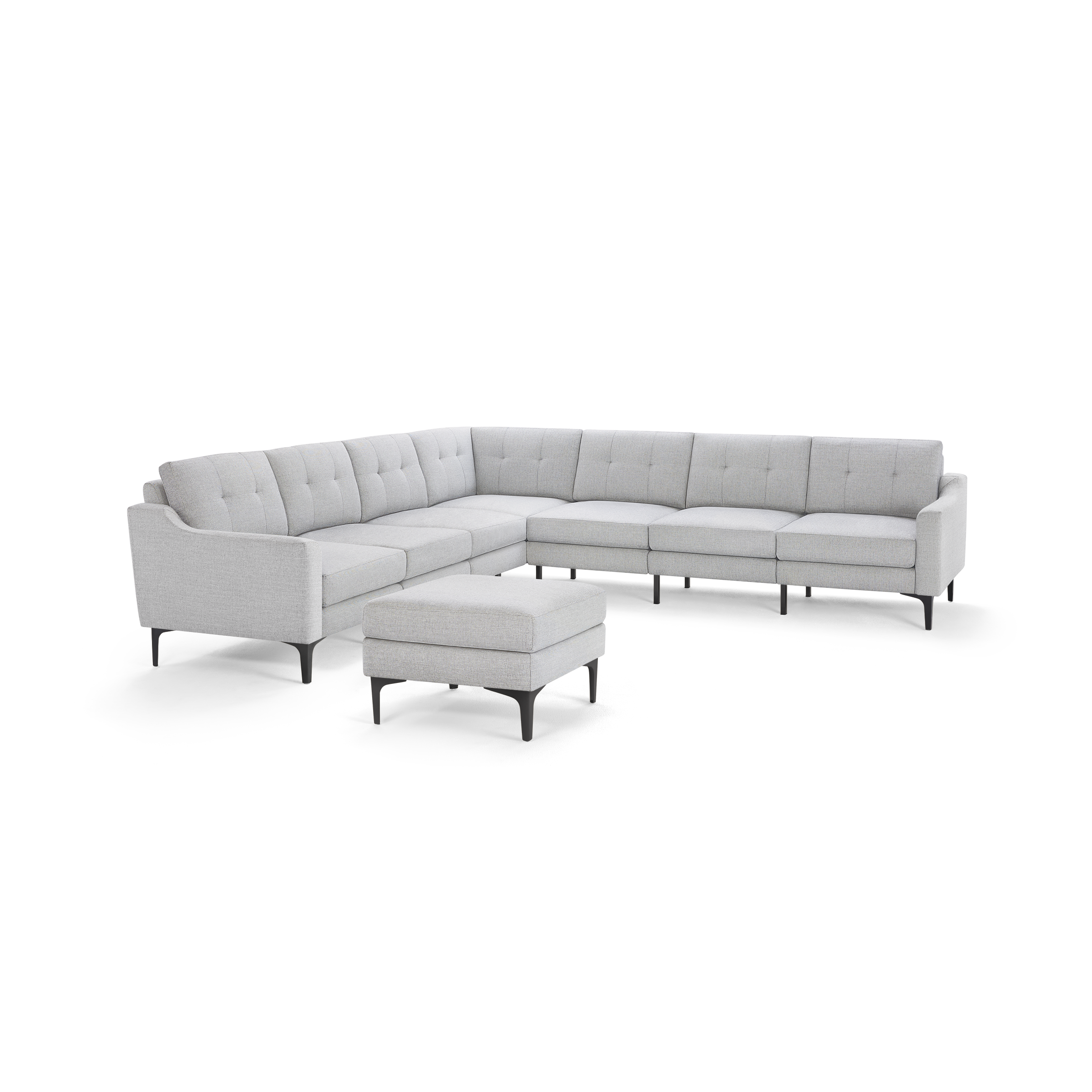 Light gray modern L-shaped sectional sofa with tufted back cushions and matching ottoman, supported by slim black legs.