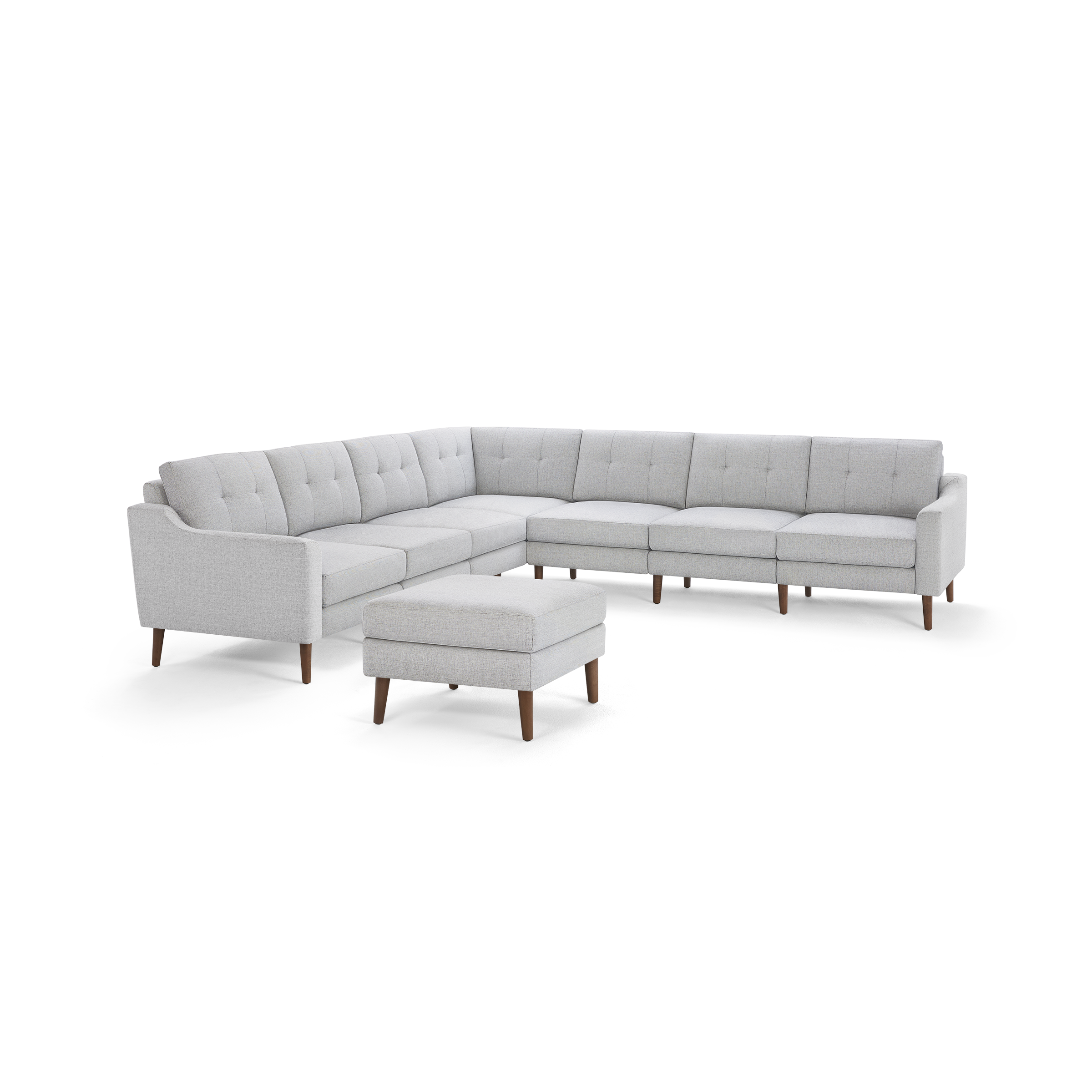 Light gray fabric sectional sofa with tufted back cushions and matching ottoman, featuring wooden legs and modern design.