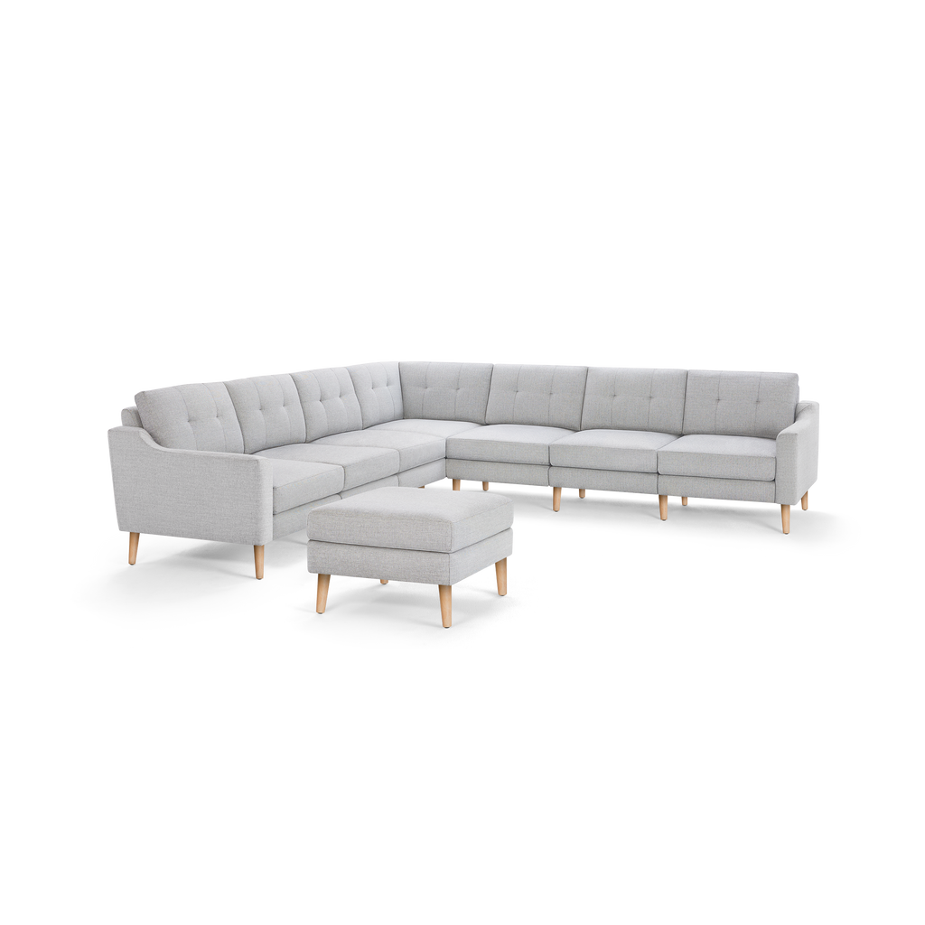 Light gray fabric sectional sofa with tufted cushions and wooden legs, accompanied by a matching ottoman.
