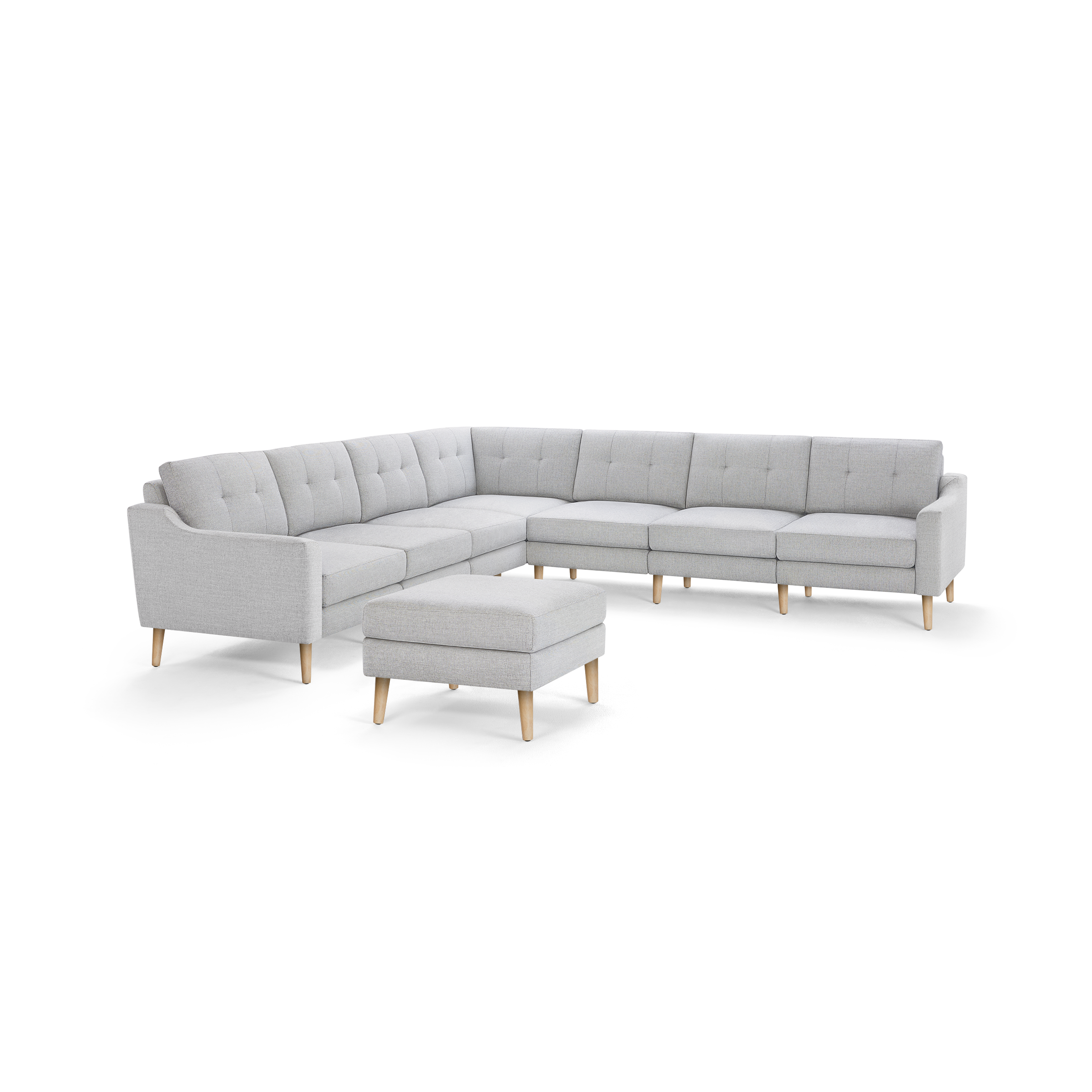 Light gray fabric sectional sofa with tufted cushions and wooden legs, accompanied by a matching ottoman.