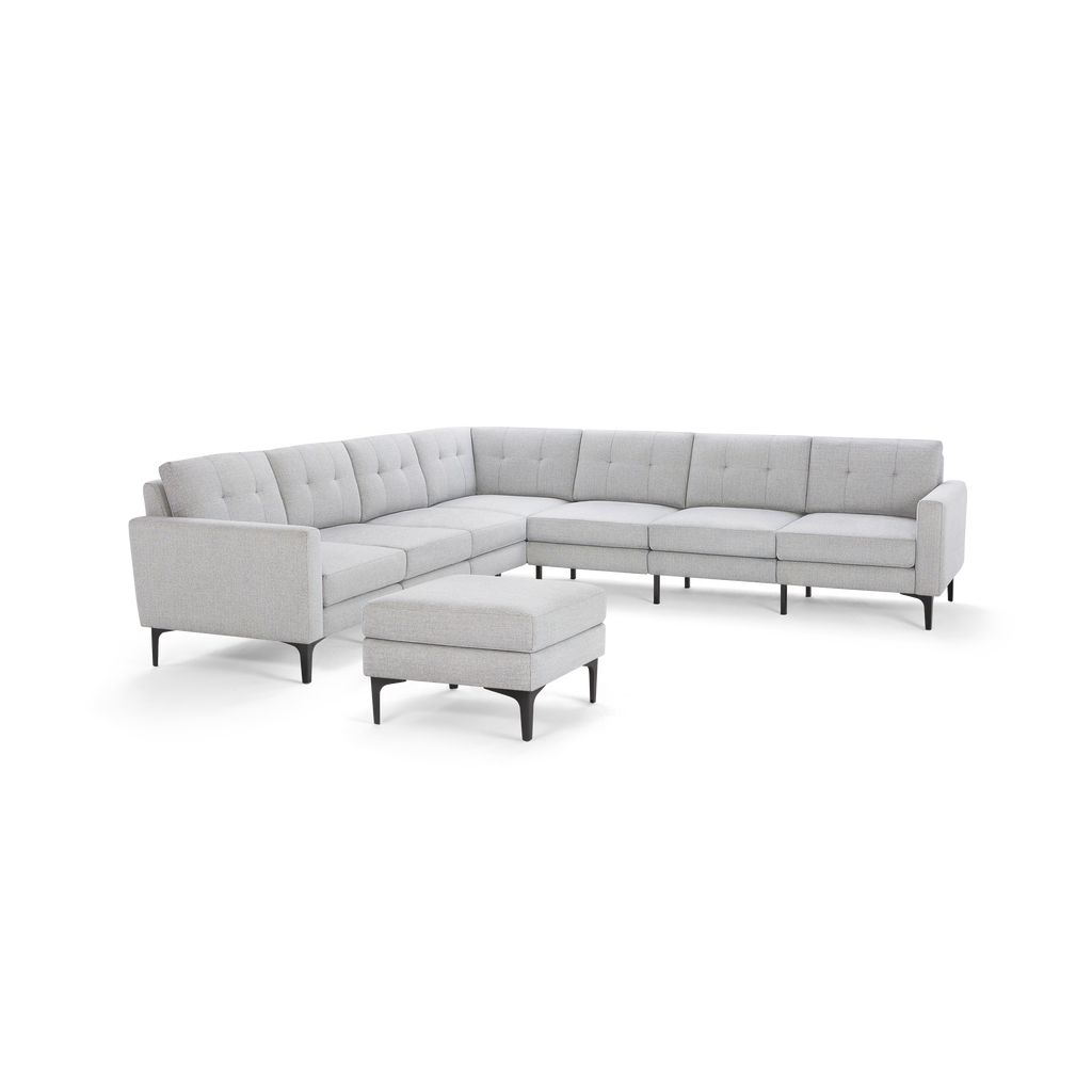 Light gray L-shaped sectional sofa with tufted back cushions and a matching ottoman, supported by black metal legs.