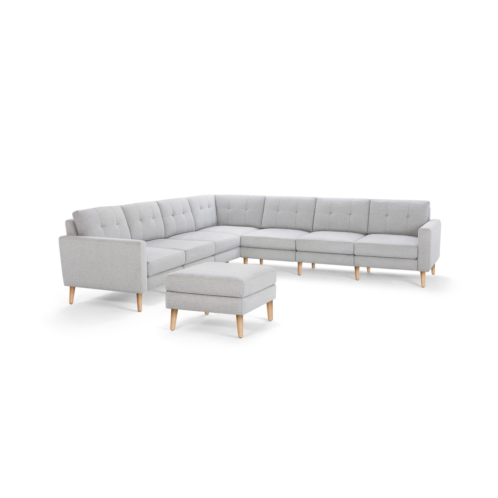 Light gray L-shaped sectional sofa with tufted cushions, wooden legs, and matching ottoman, modern minimalist design.