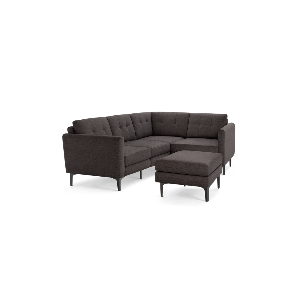 Dark gray upholstered L-shaped sectional sofa with tufted back cushions and matching ottoman on black metal legs.