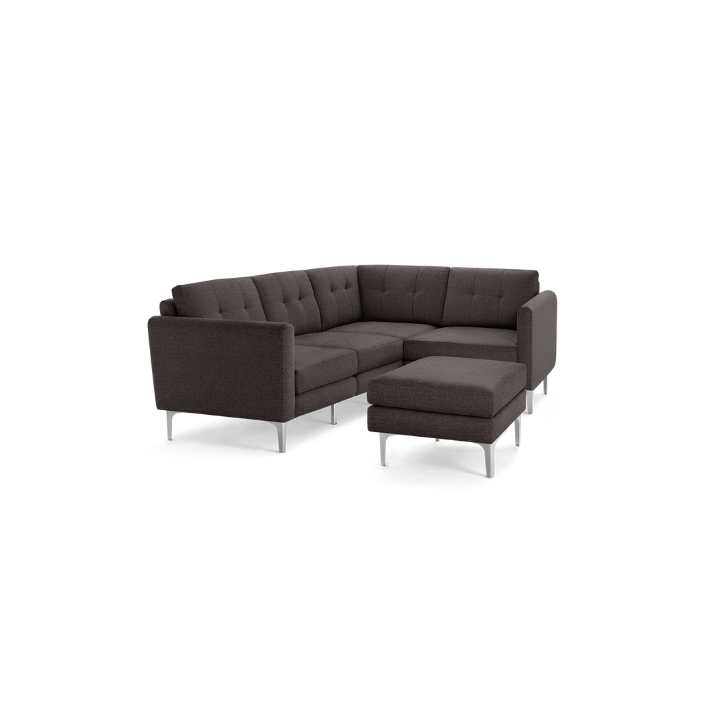 Dark gray fabric L-shaped sectional sofa with tufted back cushions and matching ottoman on silver metal legs.
