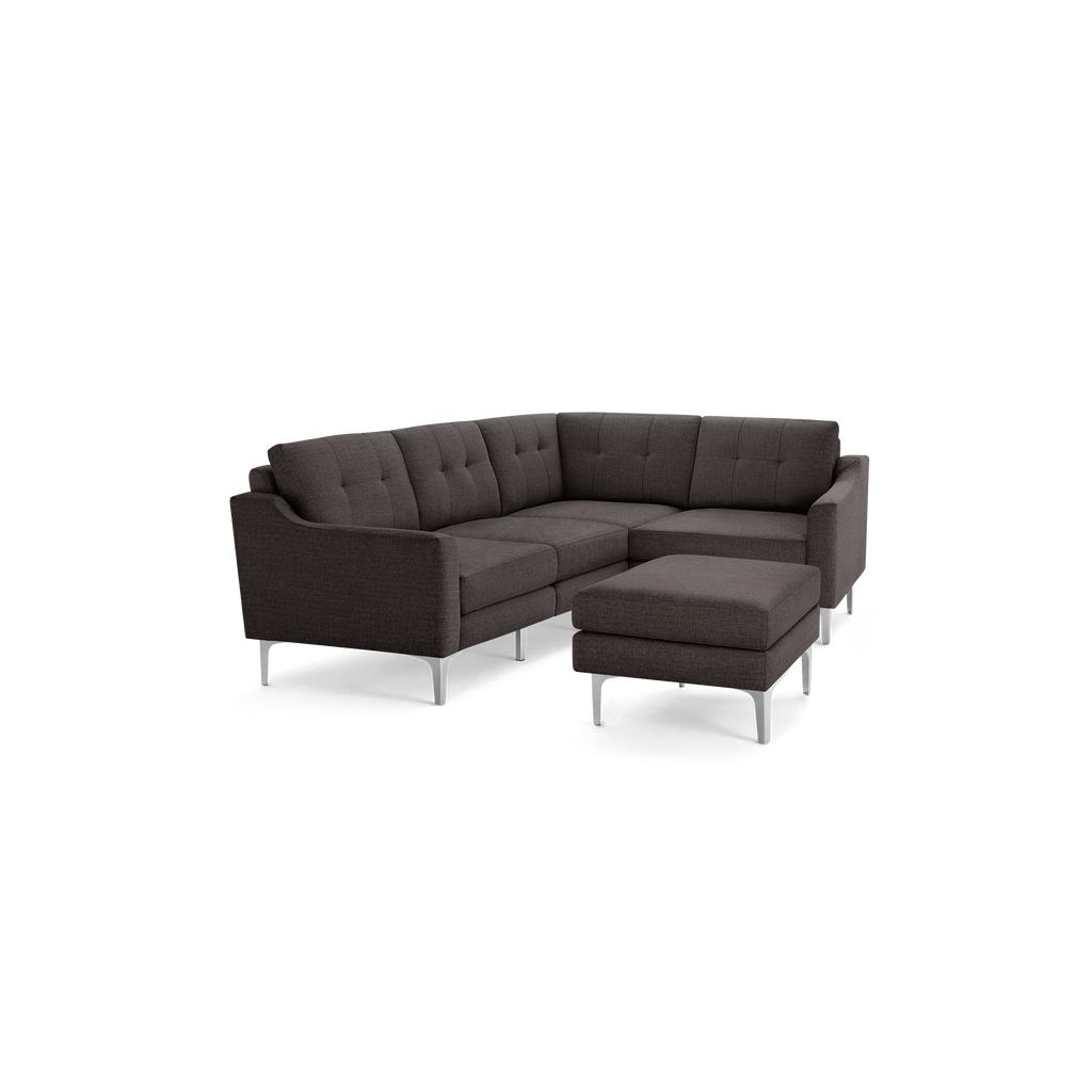 Dark gray fabric sectional sofa with tufted back cushions and matching ottoman, featuring sleek silver metal legs.