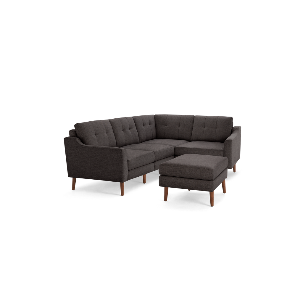 Dark gray upholstered L-shaped sectional sofa with tufted cushions and wooden legs, paired with matching ottoman.