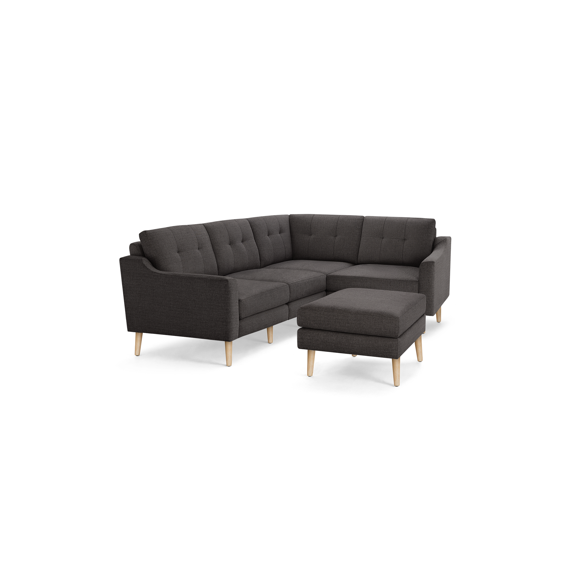 Dark gray fabric tufted L-shaped sectional sofa with angled wooden legs and matching ottoman on black background.