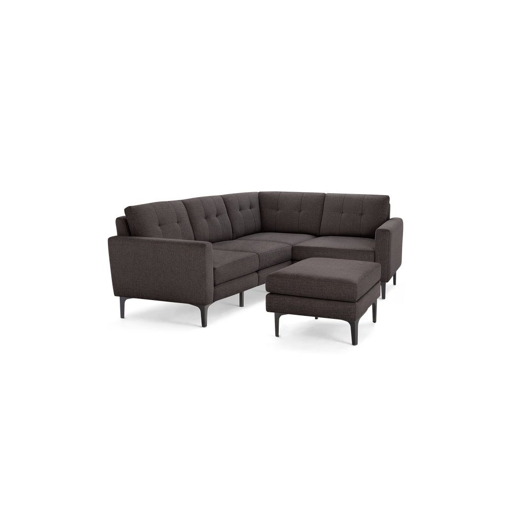 L-shaped dark gray sectional sofa with tufted back cushions and a matching ottoman on slender black metal legs.