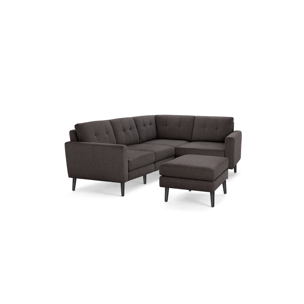 Dark gray L-shaped sectional sofa with tufted back cushions, matching ottoman, and slender black legs, modern and minimalist design.