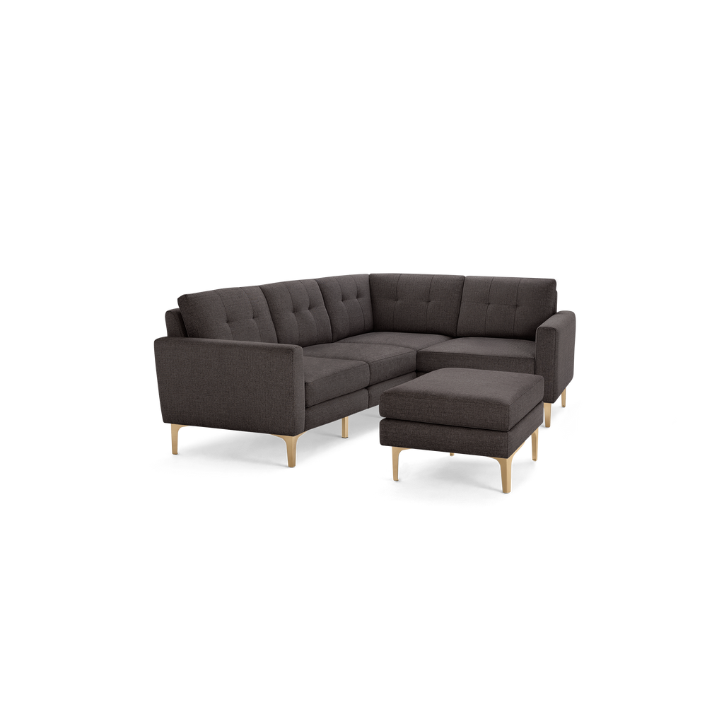 Dark gray L-shaped tufted fabric sectional sofa with wooden legs and matching ottoman.