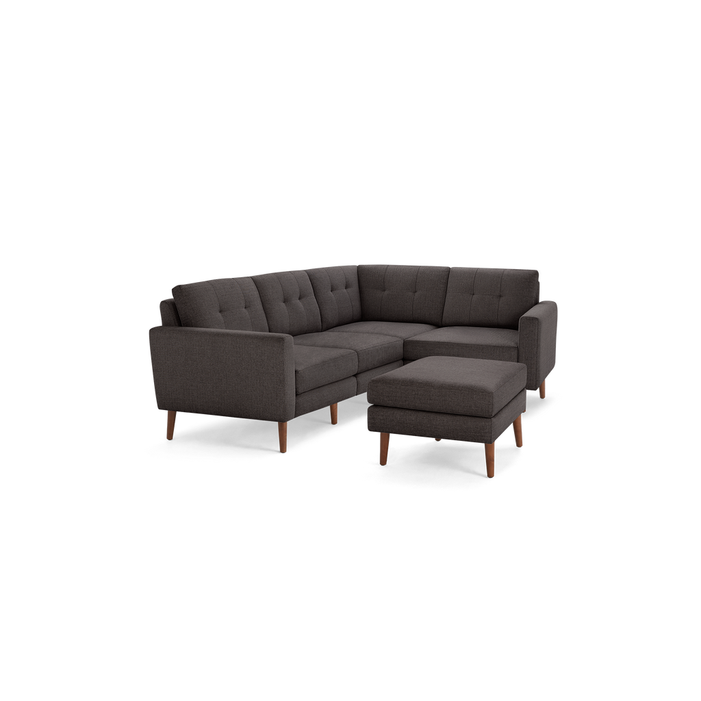 Dark gray fabric L-shaped sectional sofa with tufted cushions and wooden legs, including a matching ottoman.