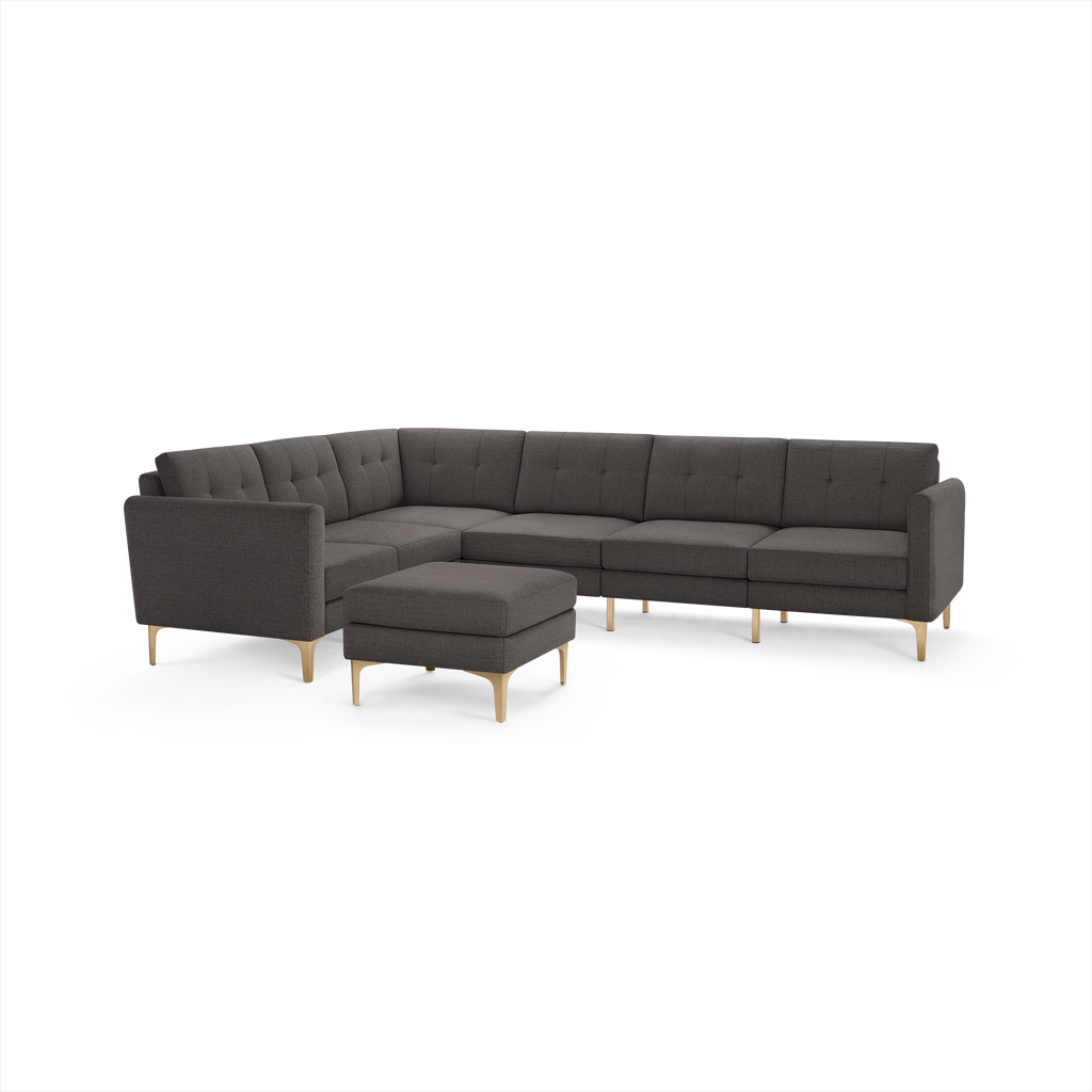 Dark gray fabric sectional sofa with tufted cushions, wooden legs, and matching ottoman, featuring an L-shaped design for ample seating.