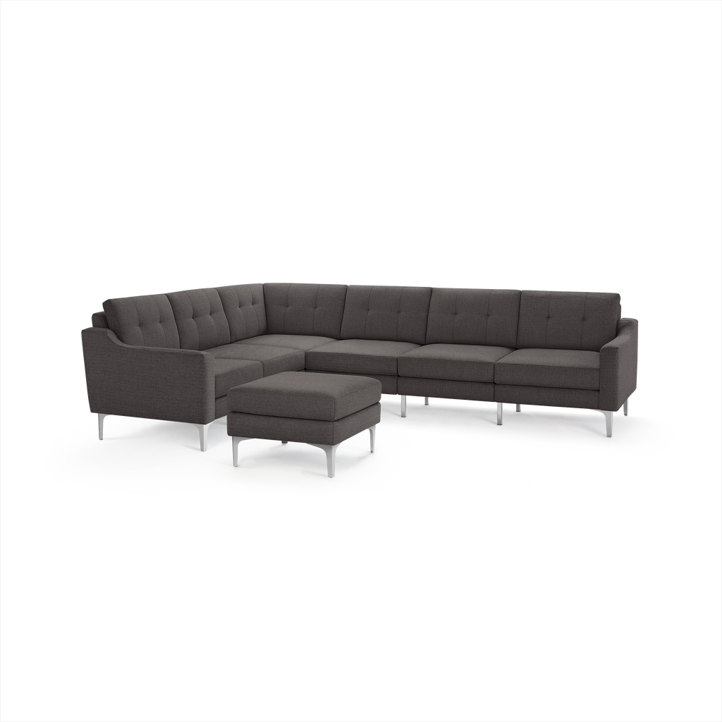Dark gray fabric L-shaped sectional sofa with tufted back cushions, slim armrests, silver metal legs, and matching ottoman.