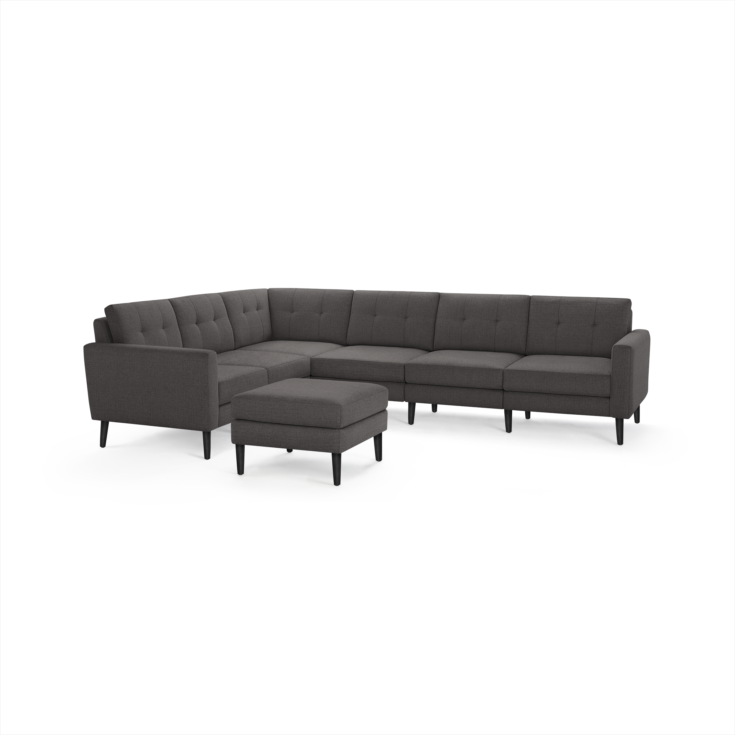 Dark gray upholstered sectional sofa with tufted back cushions, slim armrests, black angled legs, and a matching ottoman.