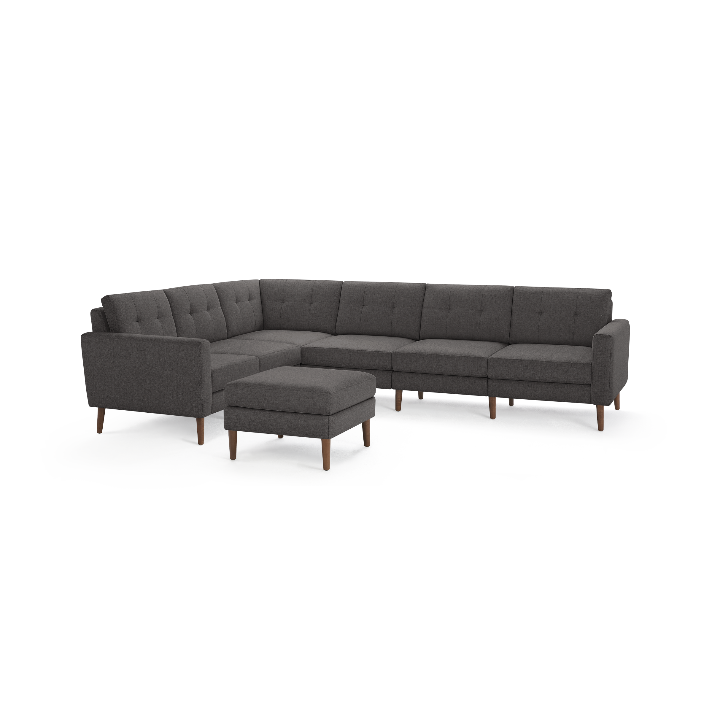 Dark gray L-shaped sectional sofa with tufted cushions and matching ottoman, supported by wooden legs.