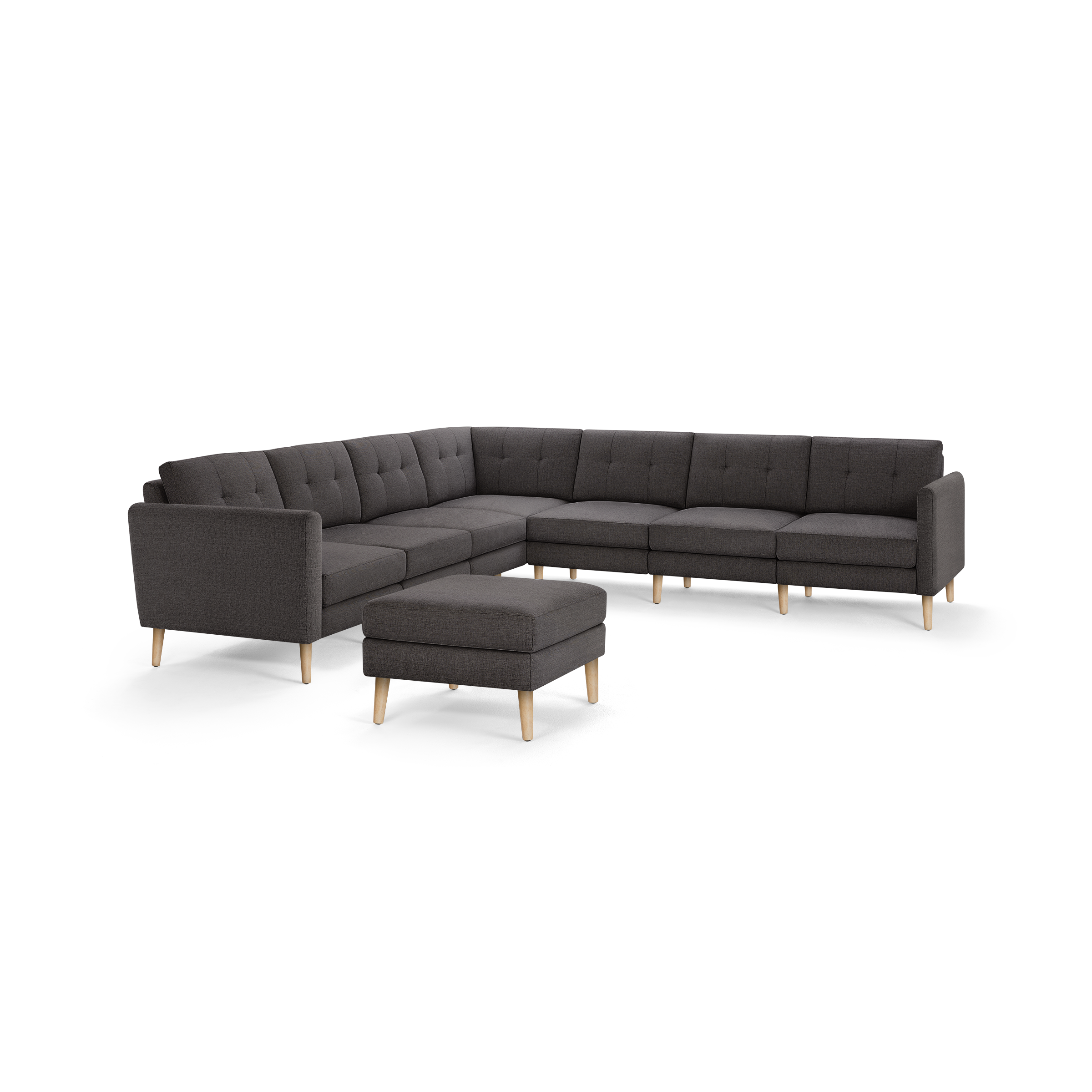 Dark gray fabric L-shaped sectional sofa with tufted cushions and light wooden legs, accompanied by a matching ottoman.
