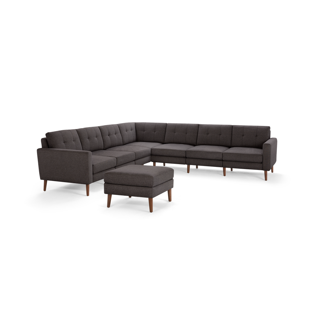 Dark gray fabric upholstered mid-century modern sectional sofa with tufted back cushions and matching ottoman, supported by wooden legs.
