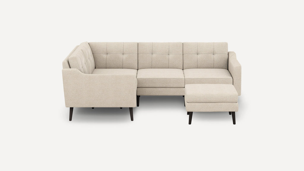 Beige L-shaped sectional sofa with tufted back cushions, paired with a matching ottoman and dark wooden legs.