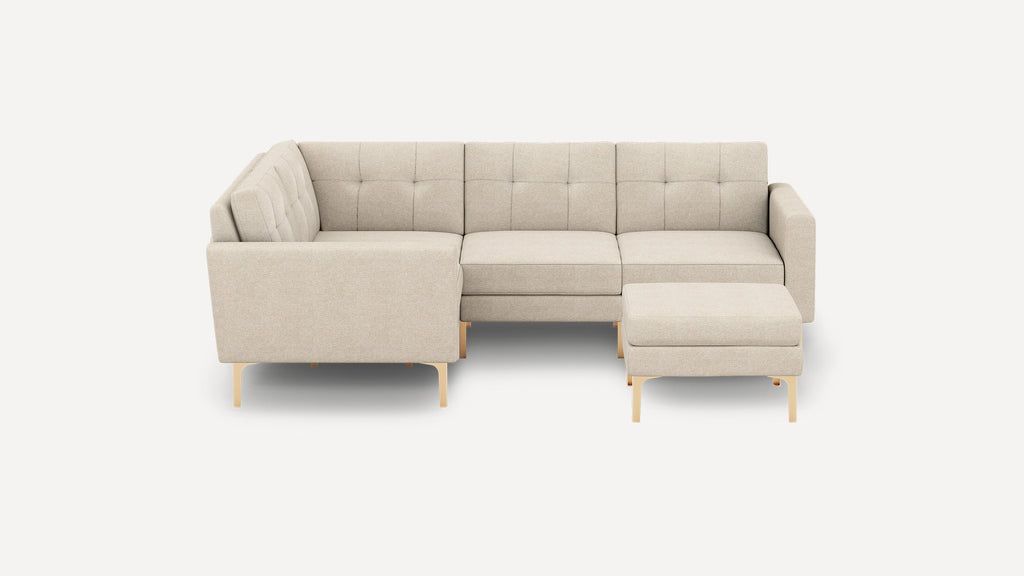 Beige modern L-shaped sectional sofa with tufted back cushions and matching ottoman, supported by slender wooden legs.