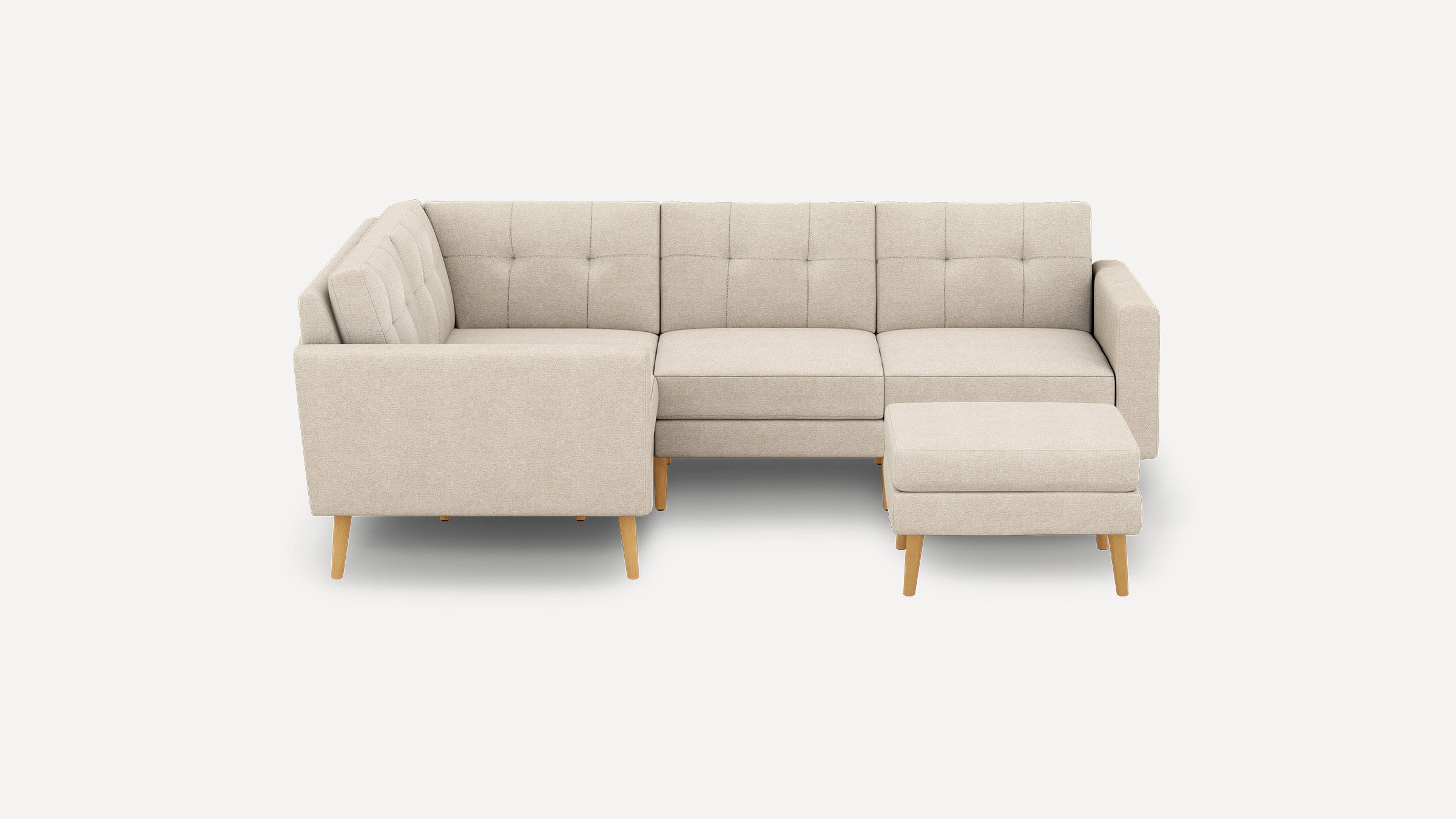 Beige L-shaped sectional sofa with tufted cushions and wooden legs, accompanied by a matching ottoman on the right side.