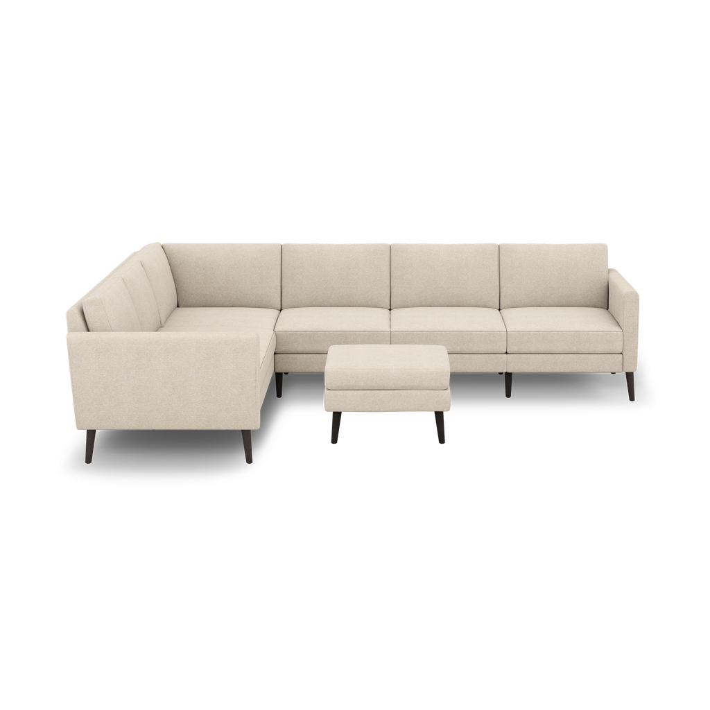 Beige fabric L-shaped sectional sofa with tufted cushions and dark wooden legs, accompanied by a matching ottoman.