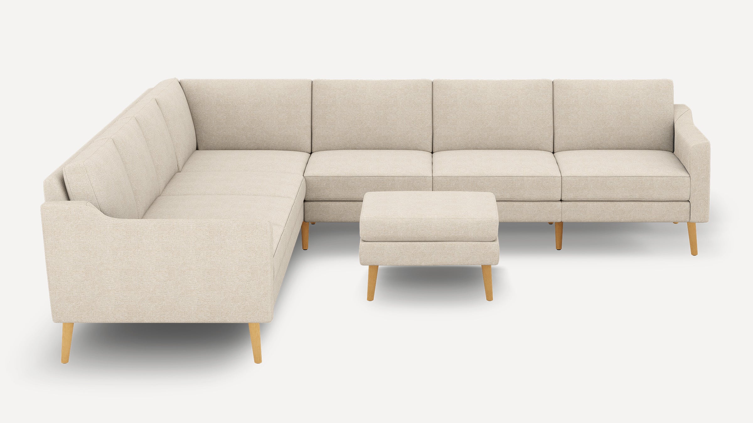 Beige L-shaped sectional sofa with wooden legs and matching ottoman, featuring clean lines and modern design.