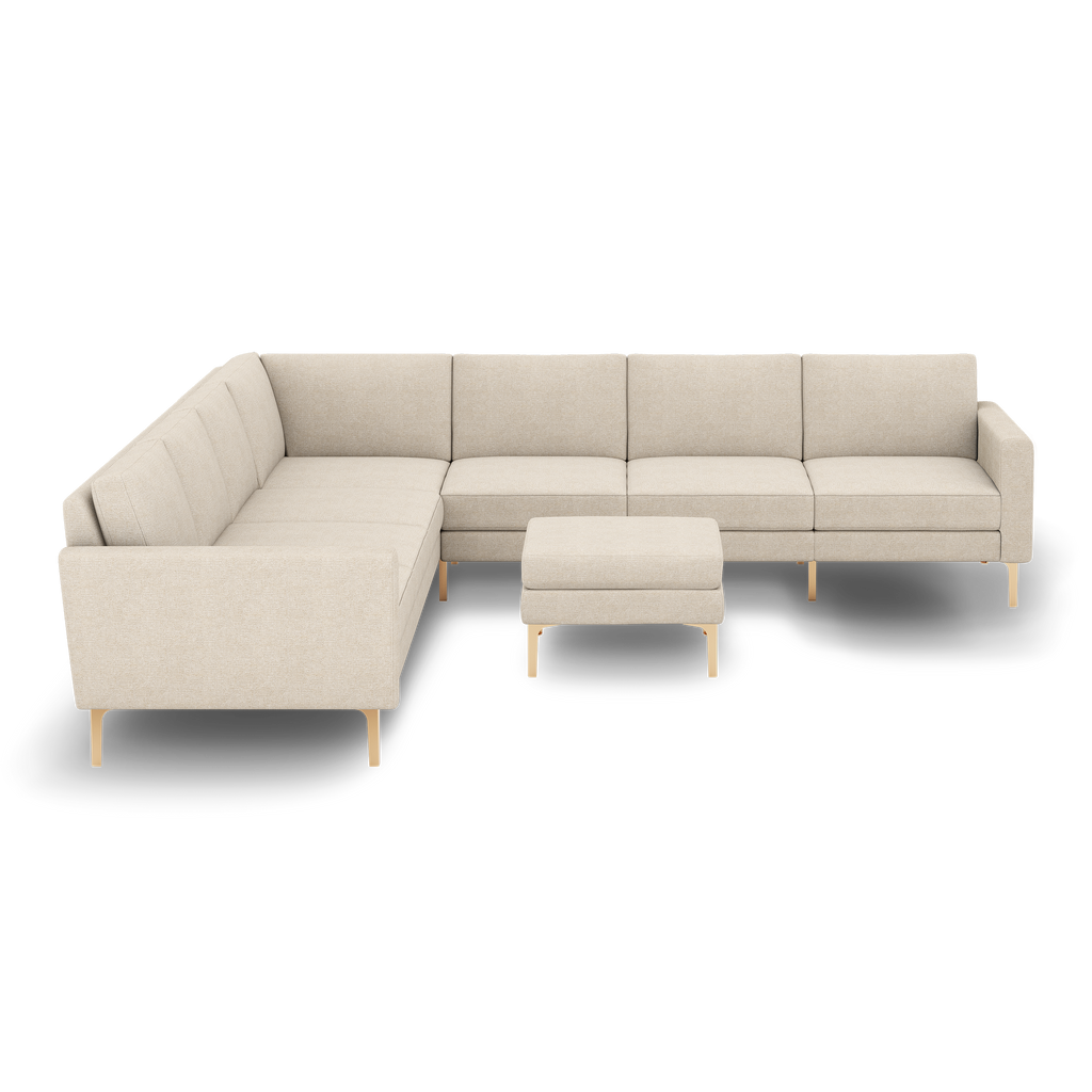 Modern L-shaped beige sectional sofa with clean lines, tufted cushions, and matching ottoman, supported by sleek gold metal legs.
