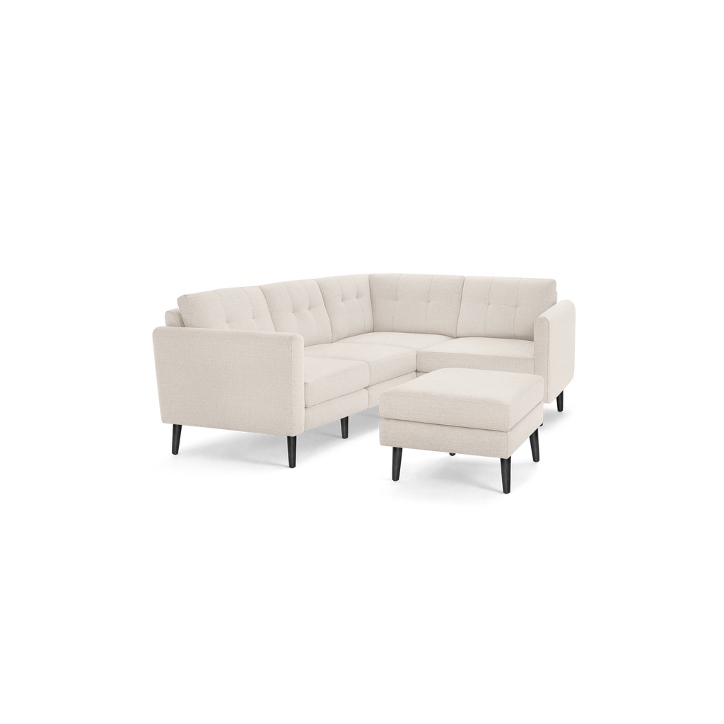 Beige modern sectional sofa with tufted back cushions, wooden legs, and matching upholstered ottoman on a black background.