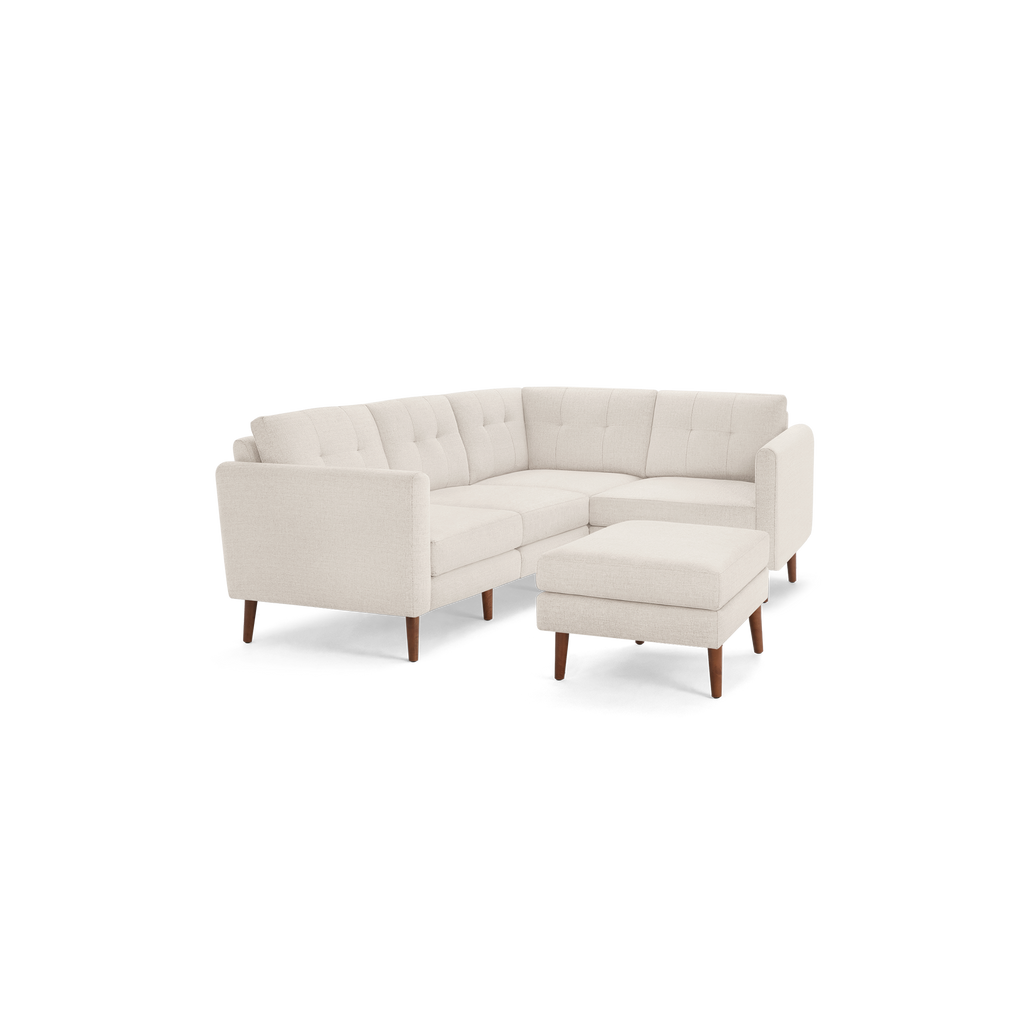 Light beige modern tufted fabric sectional sofa with wooden legs and a matching ottoman, shown on a black background.