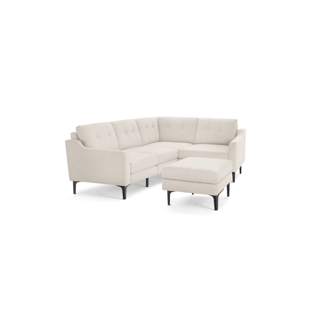Beige fabric sectional sofa with tufted back cushions and a matching ottoman, supported by black metal legs.