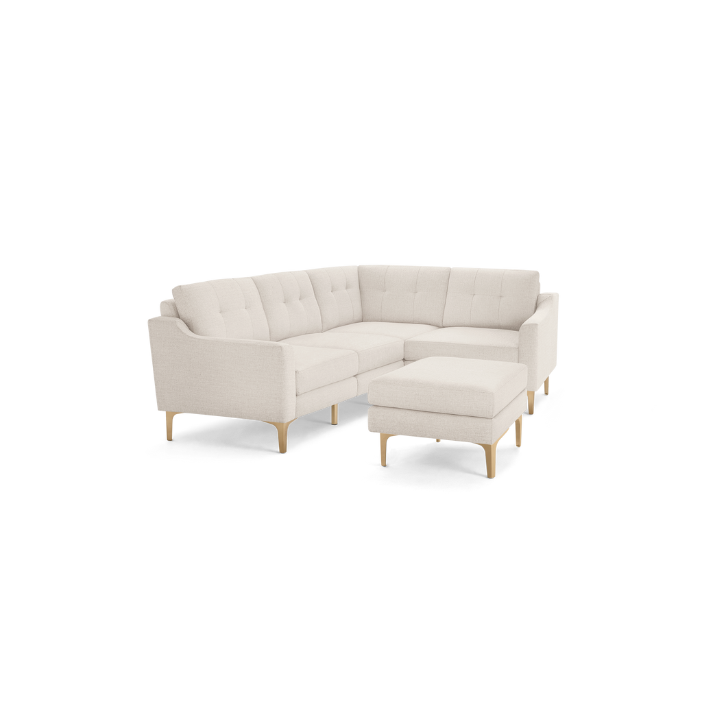 Light beige L-shaped sectional sofa with tufted back cushions and matching ottoman, featuring wooden legs.