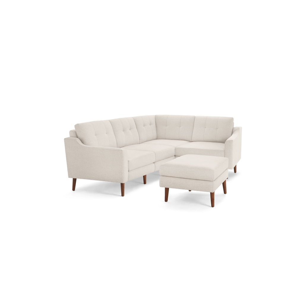 Light beige L-shaped sectional sofa with tufted back cushions, wooden legs, and matching ottoman, modern minimalist design.