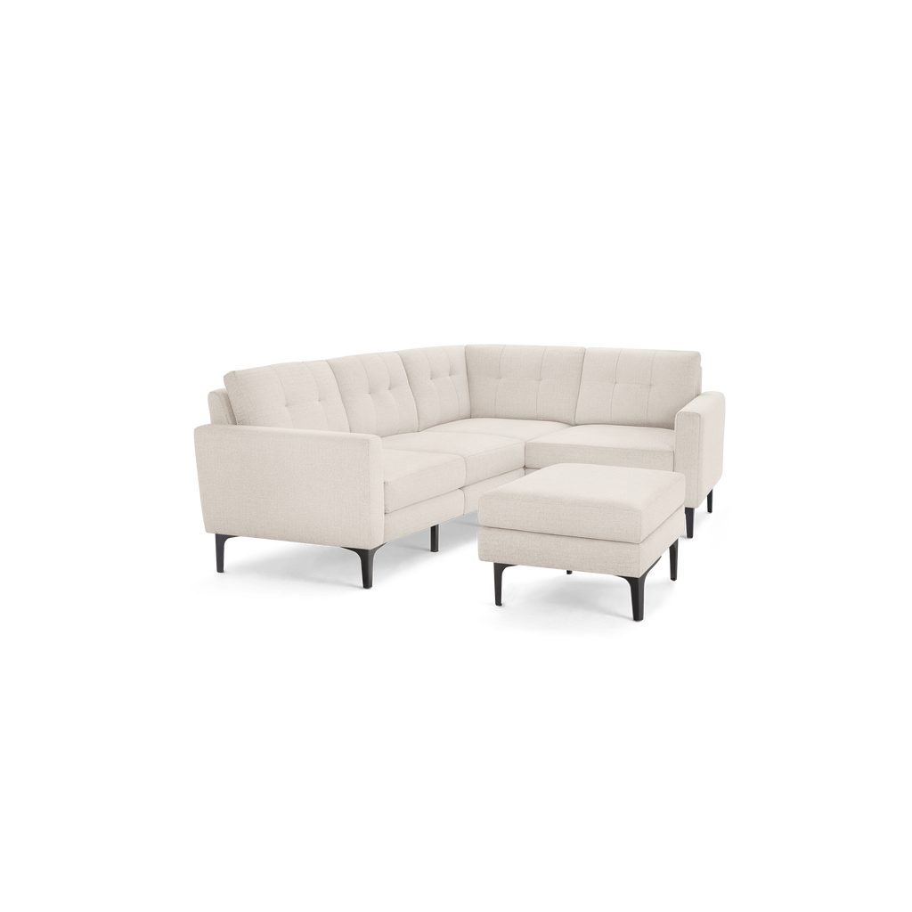 Modern beige sectional sofa with tufted back cushions and matching ottoman, featuring sleek black legs.